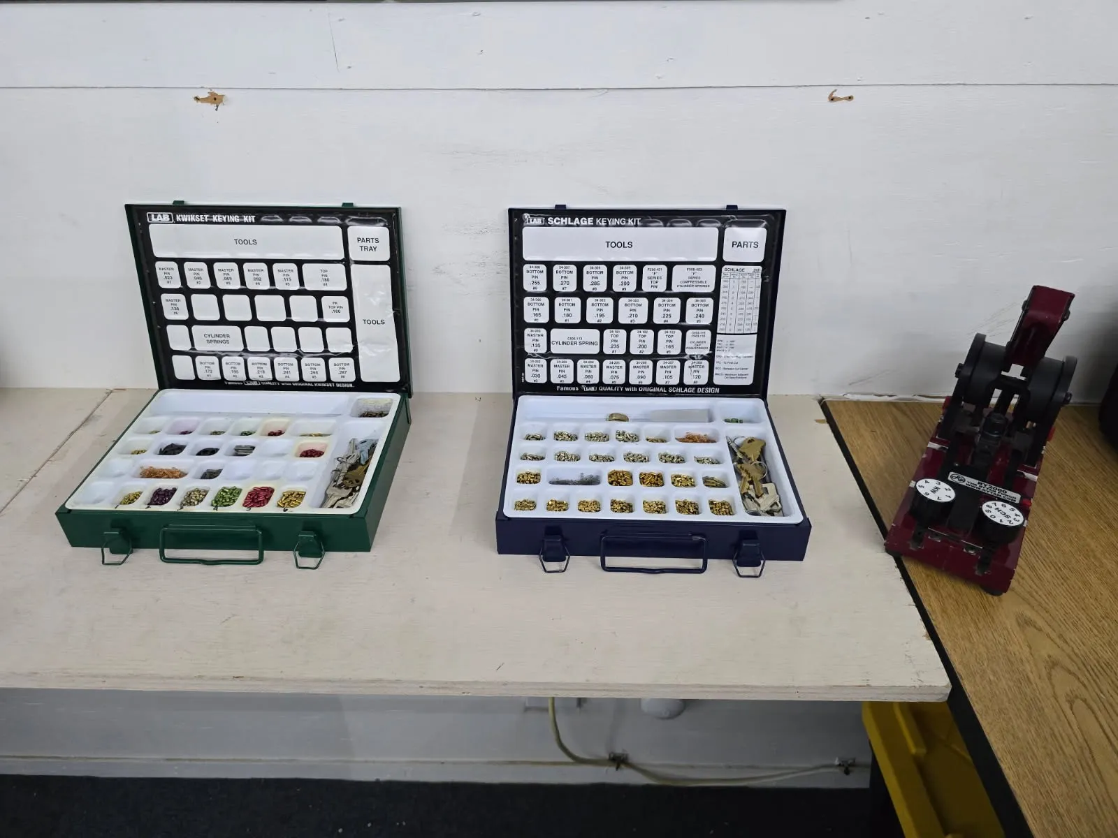 Open residential keying kits beside locksmith equipment on a workshop bench