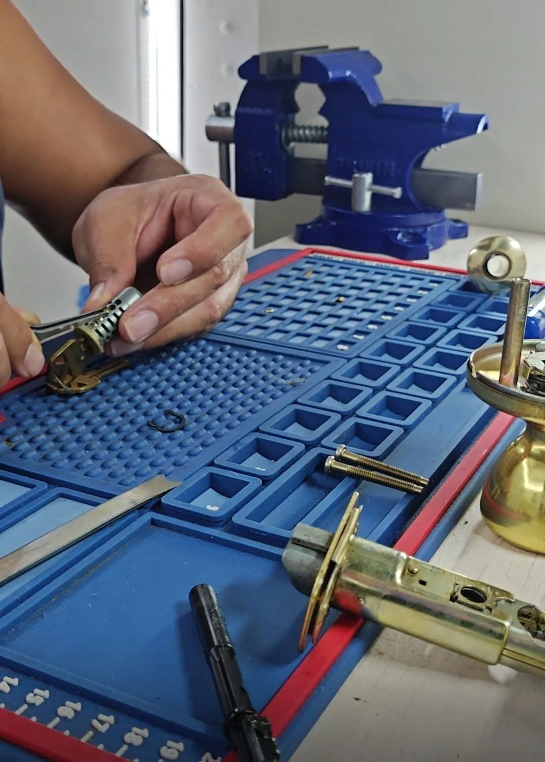 Locksmith rekeying a residential lock cylinder at a workbench